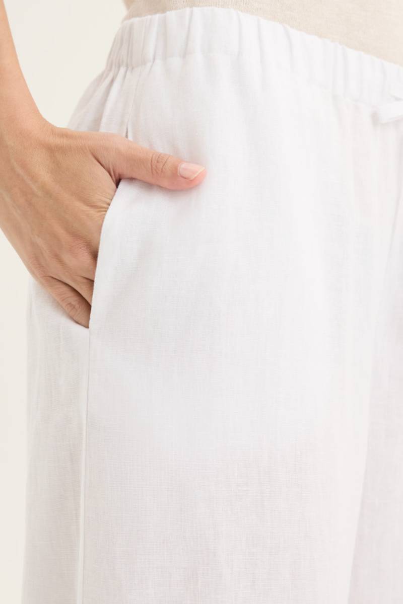 Close up view of pocket detail of model wearing Yarra Trail Tirari Palazzo Pant in 100% linen — wide-leg 7/8 length style with elastic waistband and herringbone tie.