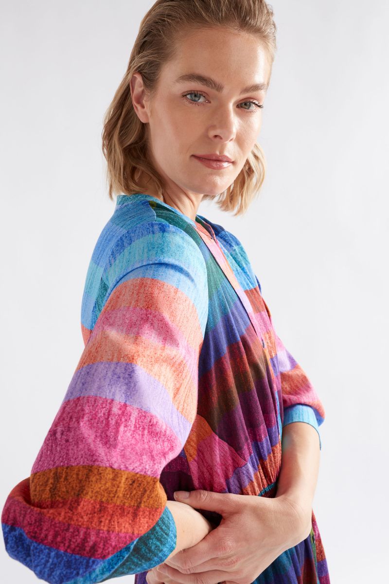 Woman wearing a colorful striped dress against a white background