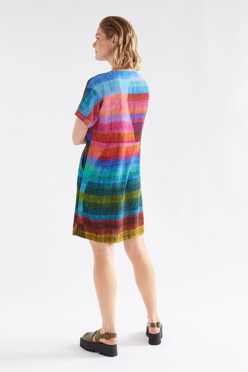 Woman wearing back view of colorful Sono striped dress on a white background