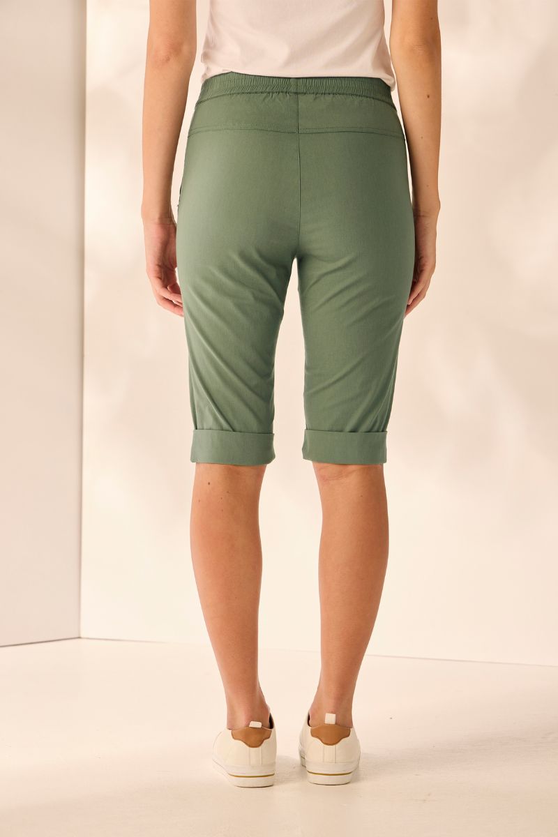 Person wearing green capri pants on a plain background