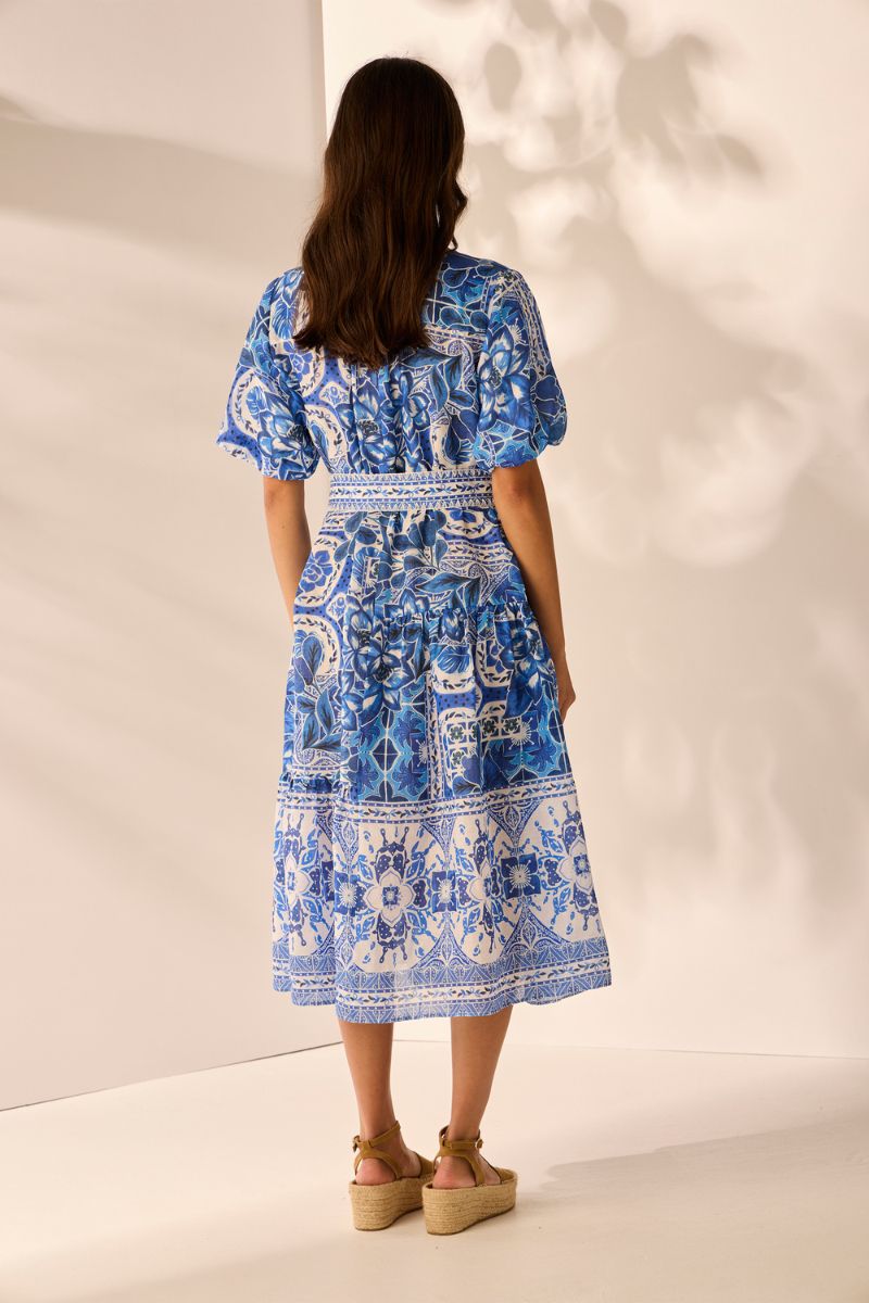 Back view Woman wearing a blue and white patterned dress against a neutral background