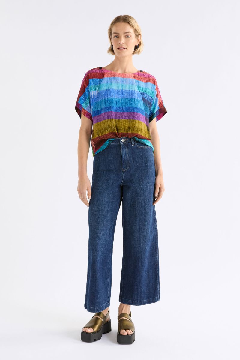 Person wearing a colorful striped shirt and blue jeans on a white background