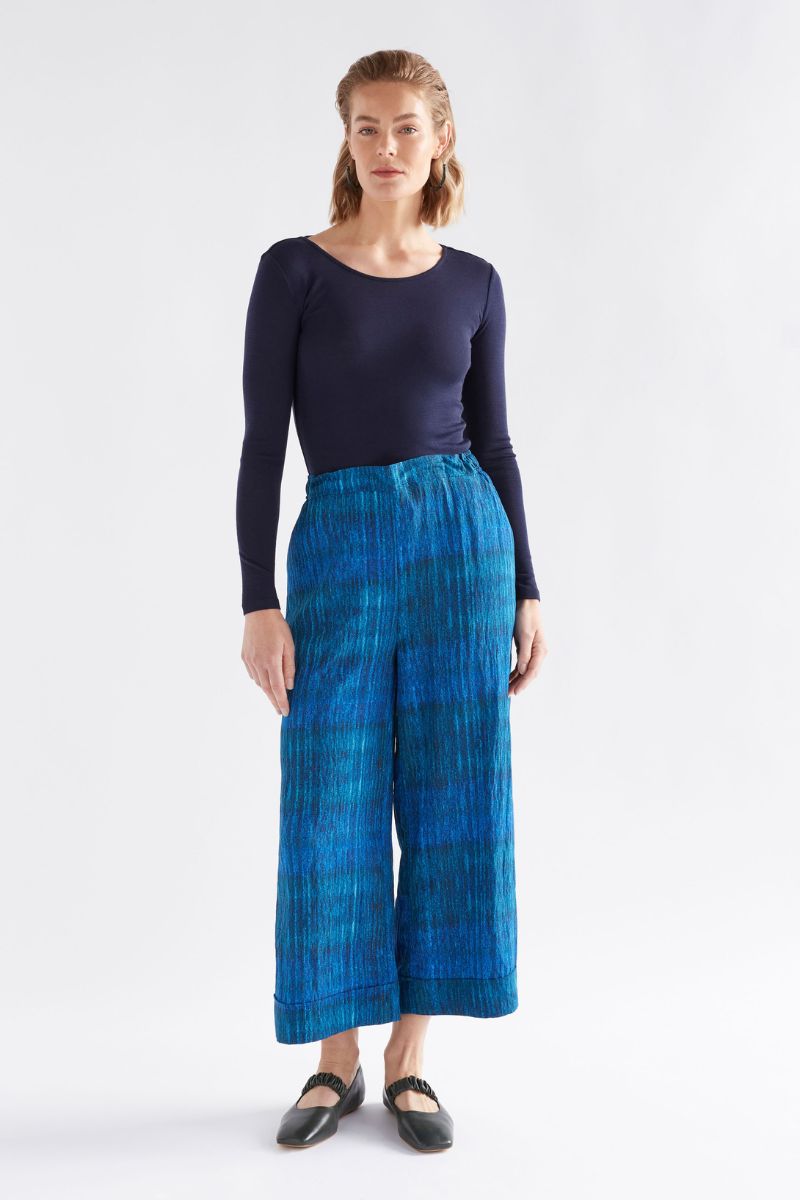Woman wearing a navy top and blue plaid pants on a white background