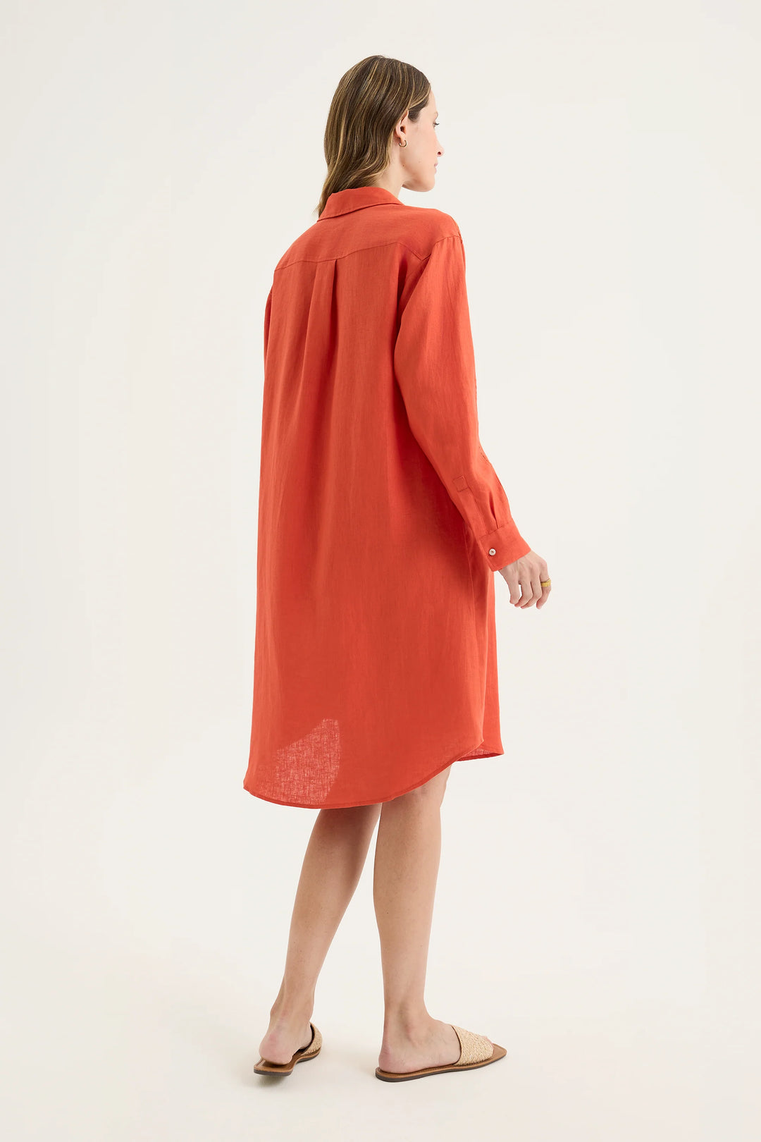 Rear view of woman wearing Yarra Trail Tirari Shirtmaker Dress in Volcanic red YTWN9639 showing hi-low hem against white background