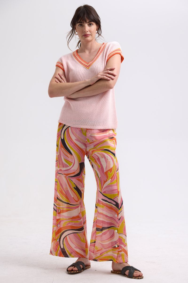 Woman wearing a pink sweater and colorful pants on a white background