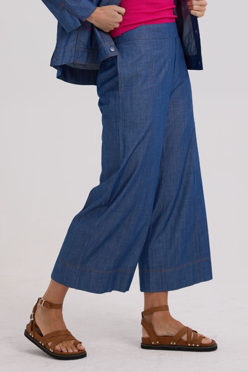 Person wearing blue wide-leg pants with a plain background