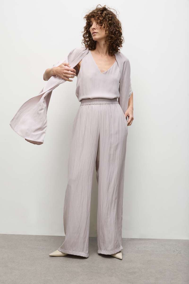 A model wearing a sleeveless, v-neckline Audrey Tank top in a solid color, showcasing a relaxed fit with a high-low hem.
