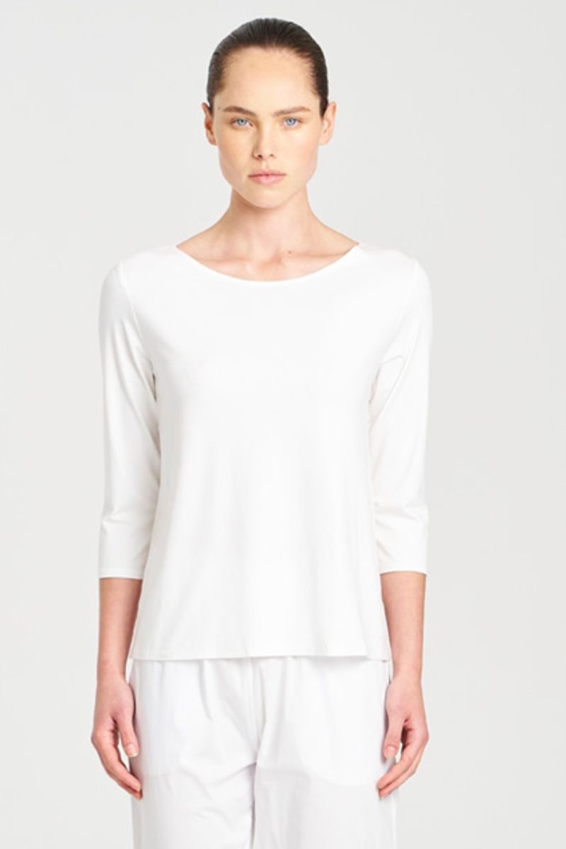Person wearing a white long-sleeve top and pants on a light gray background