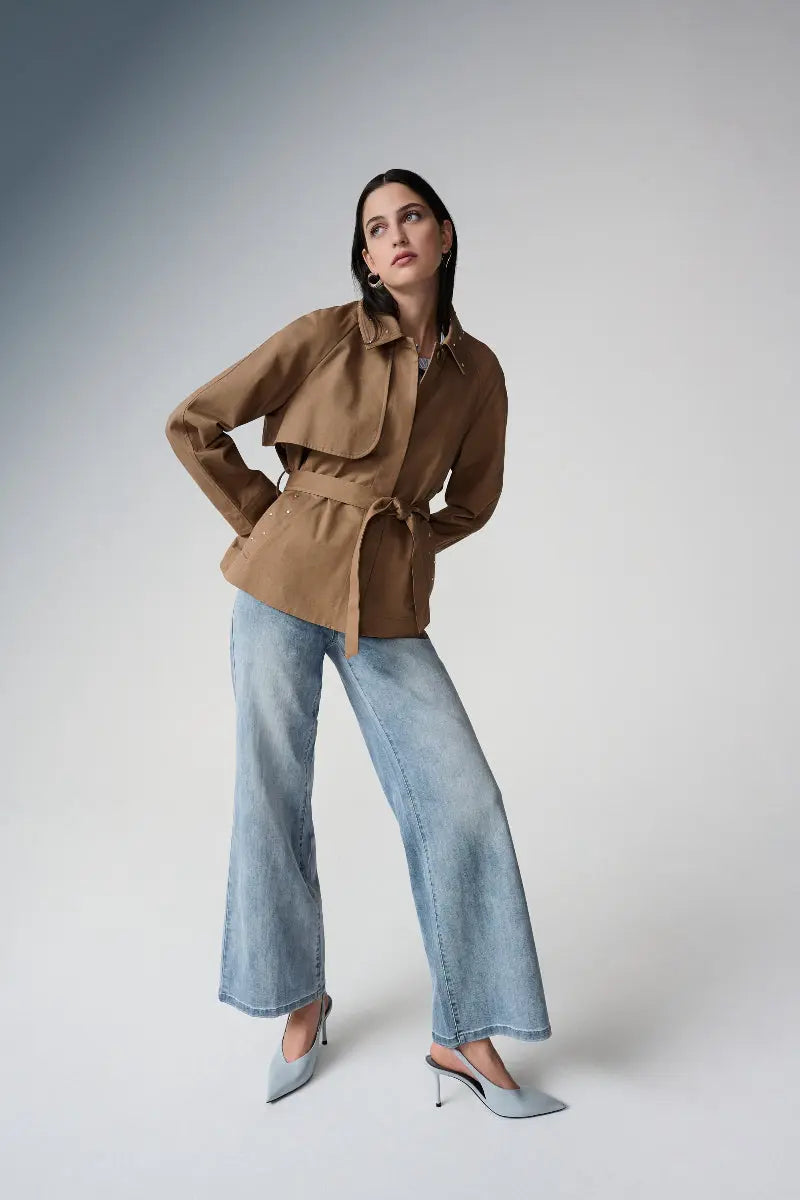 Woman wearing a Cotton Twill Short Trench with Belt and Rhinestones Detail and light blue Goldie Jeans on a gray background