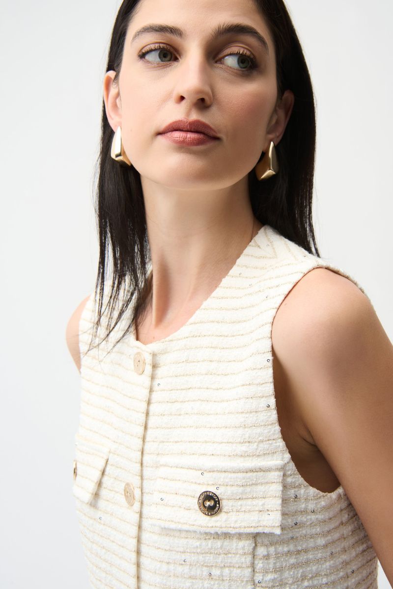 Woman wearing a white textured sleeveless top with buttons on a light background