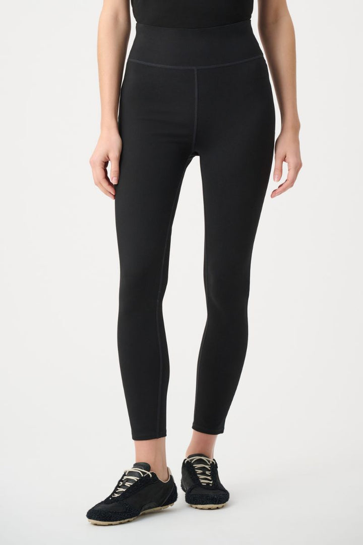 A model wearing black Joseph Ribkoff high-waisted athletic leggings and black sneakers, shown from the waist down against a plain white studio background.