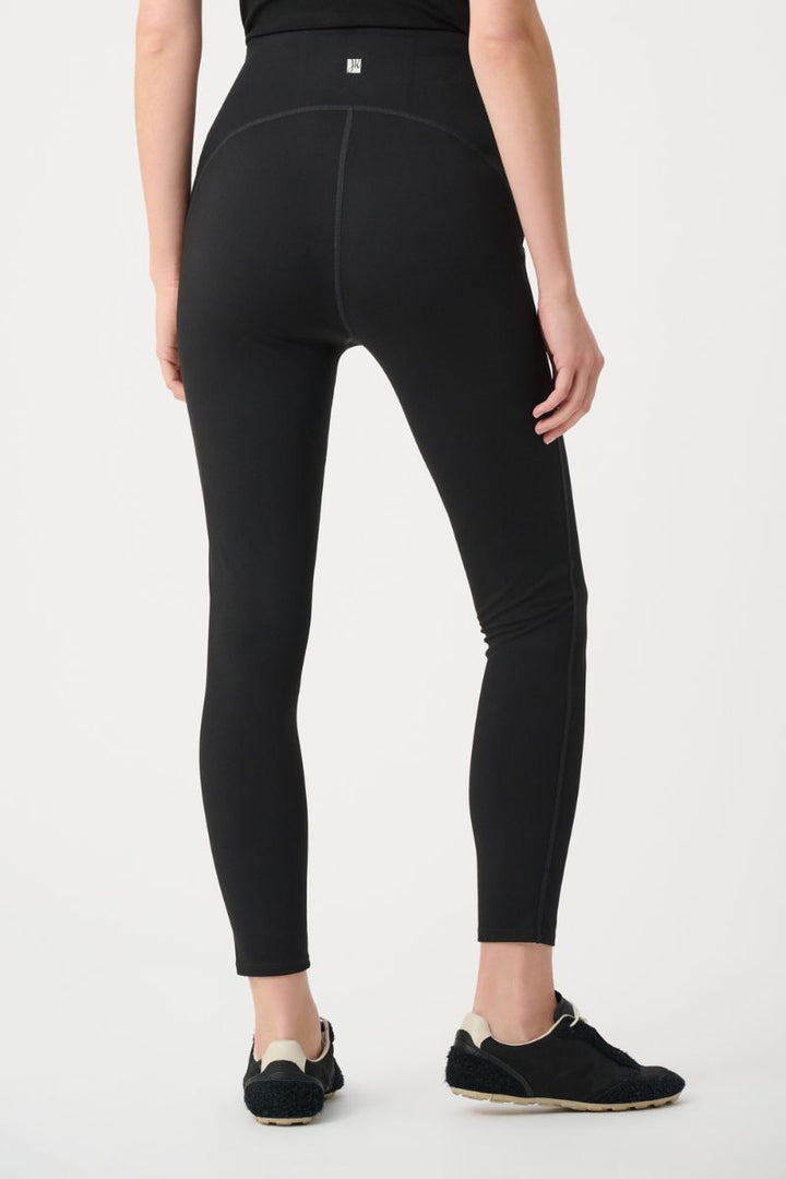 Person wearing joseph ribkoff black leggings on a white background