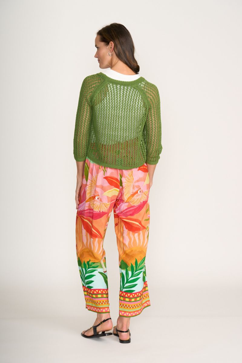 Woman wearing a green knitted sweater and colorful pants on a white background