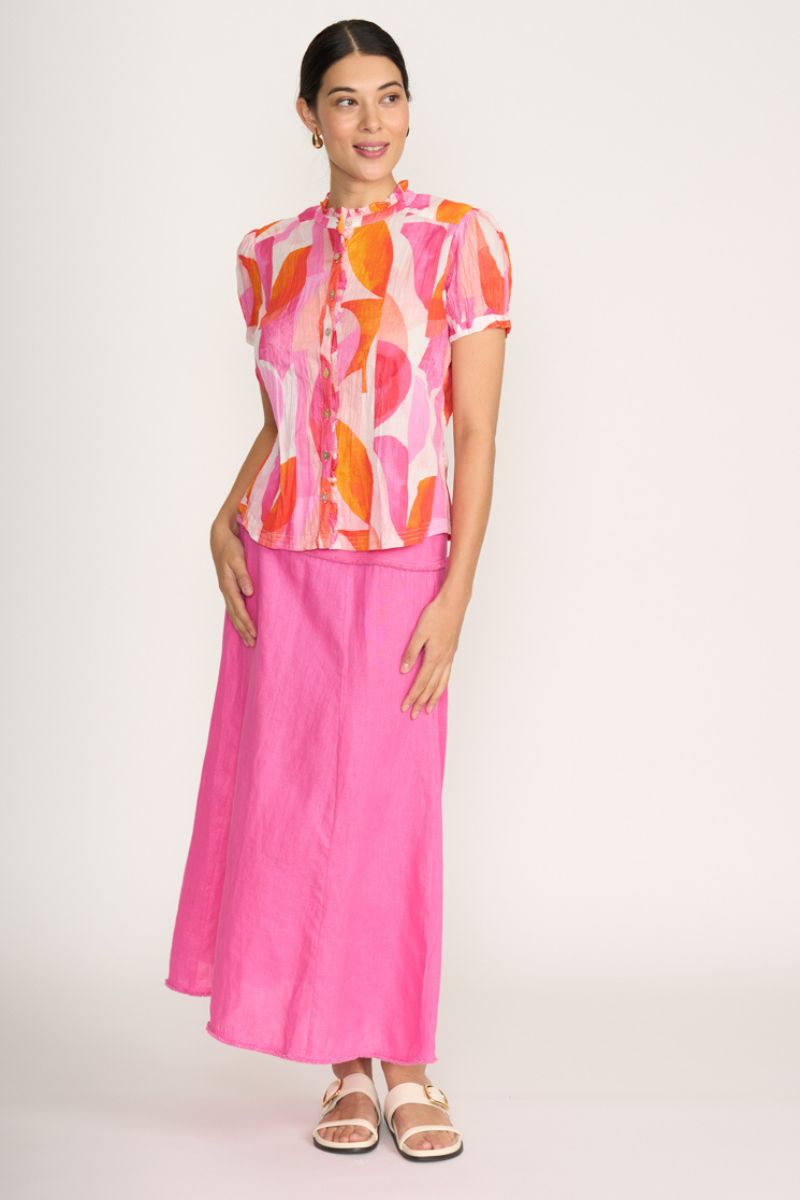 Woman wearing a colorful top and pink skirt on a white background