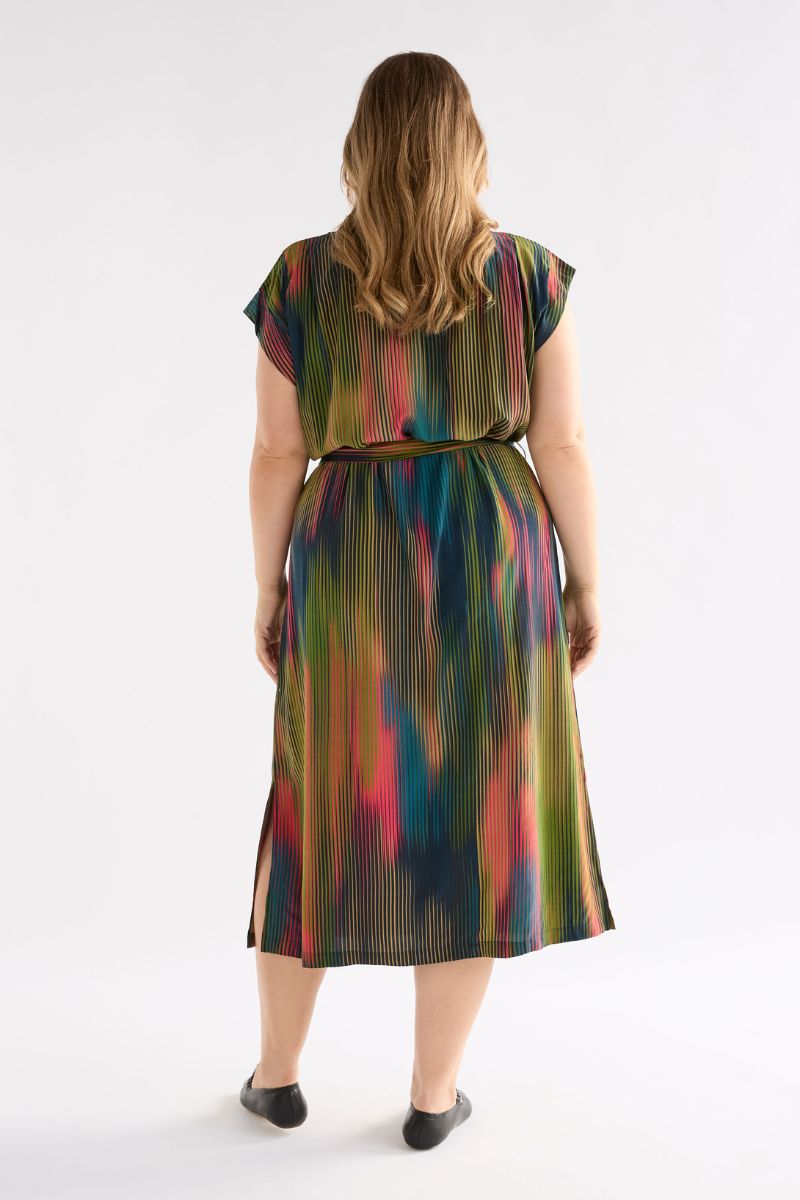 Back view of a woman wearing a colorful dress with a pattern on a white background