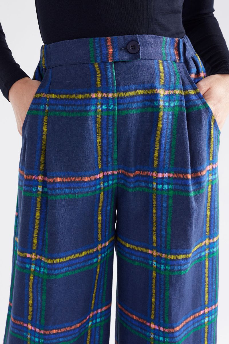 Blue plaid pants with colorful lines worn by a person on a white background