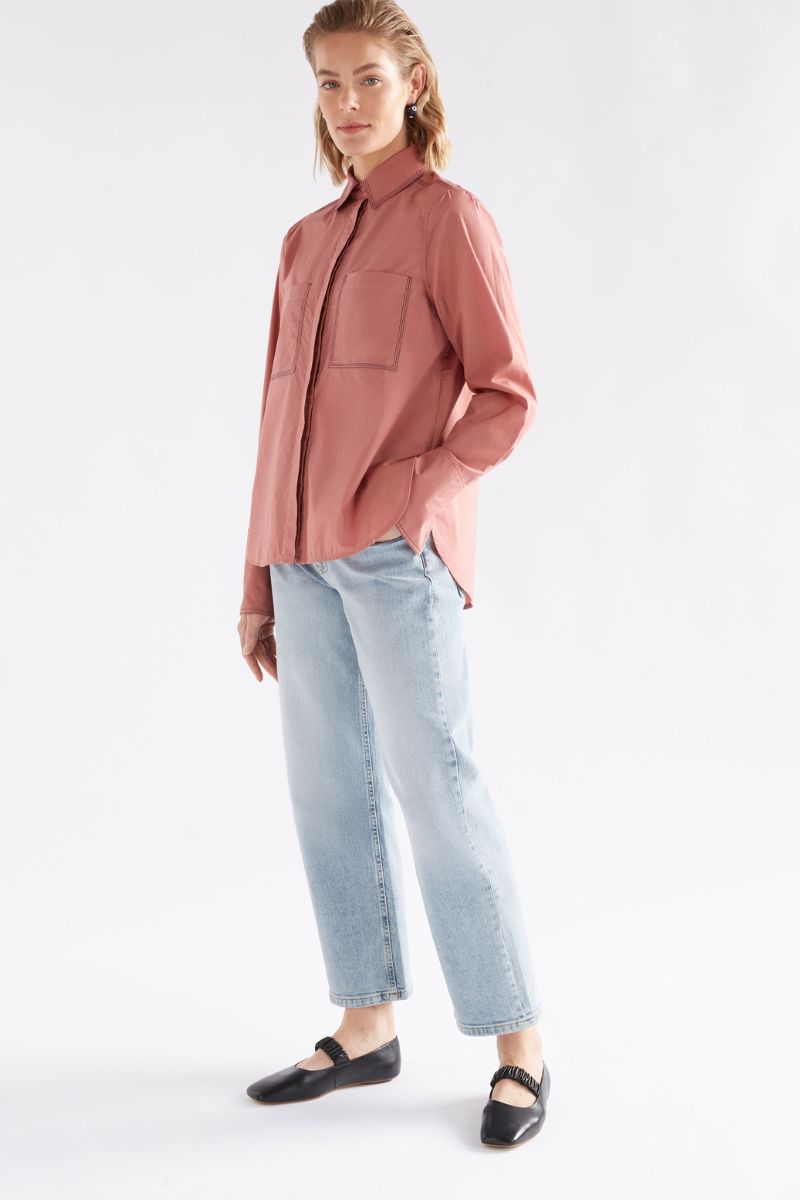 Woman wearing a pink shirt and light blue jeans on a white background