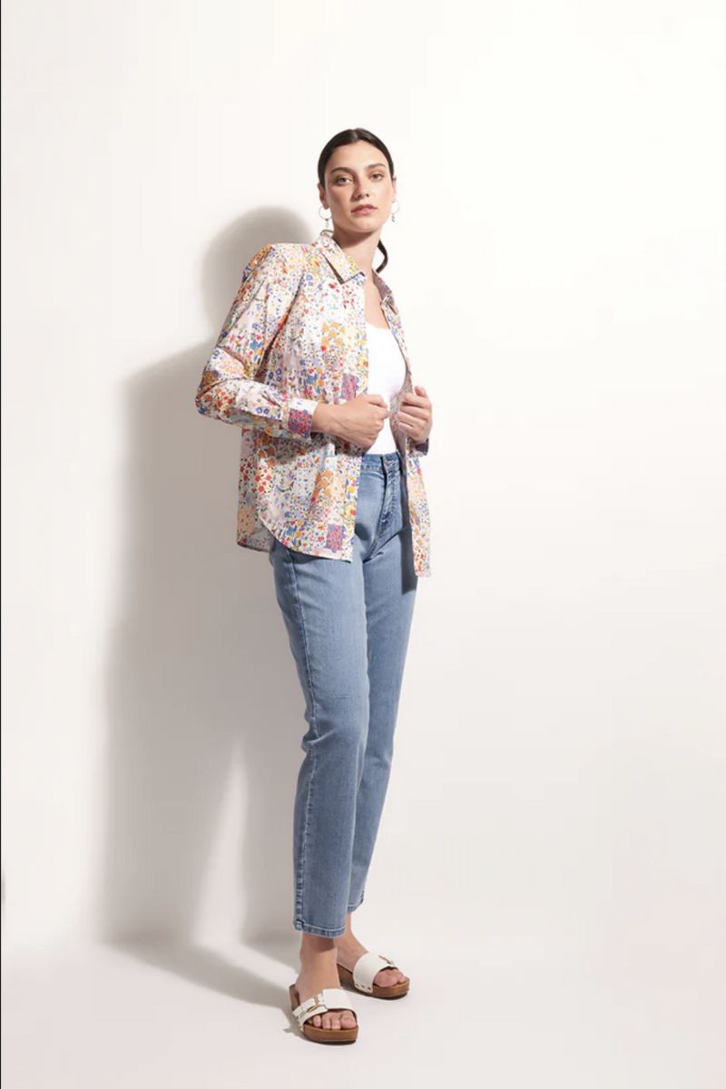 Woman wearing a floral jacket, white shirt, and blue jeans against a white background