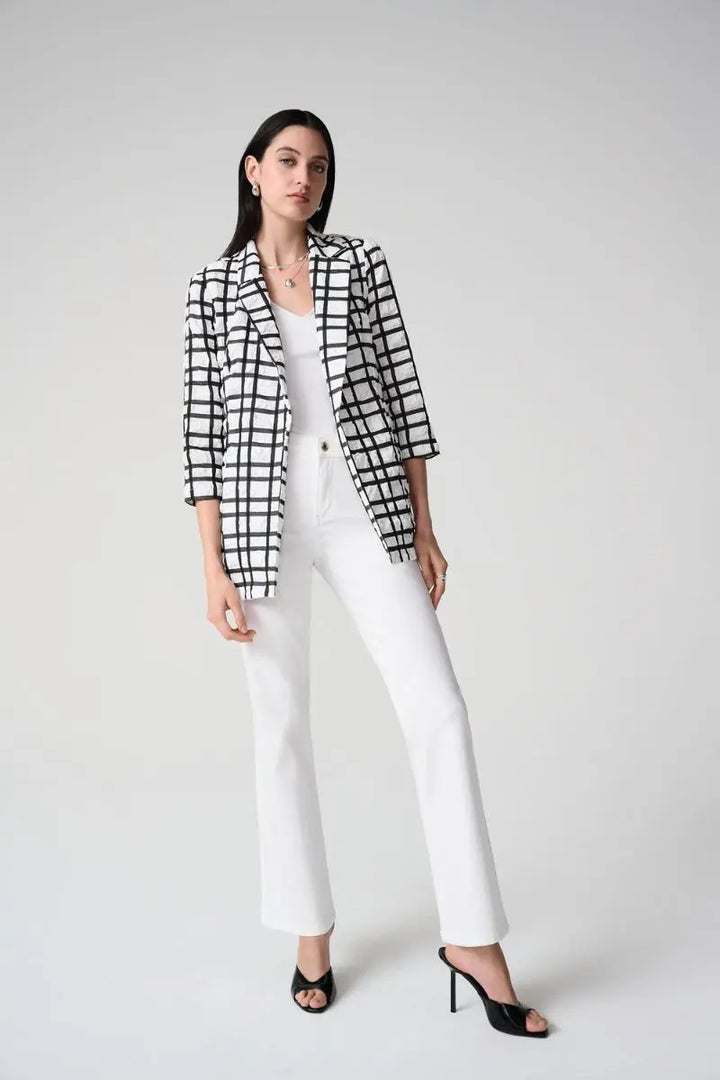 Woman wearing a Joseph Ribkoff black and white checkered blazer with white brooke featherweave jeans on a gray background