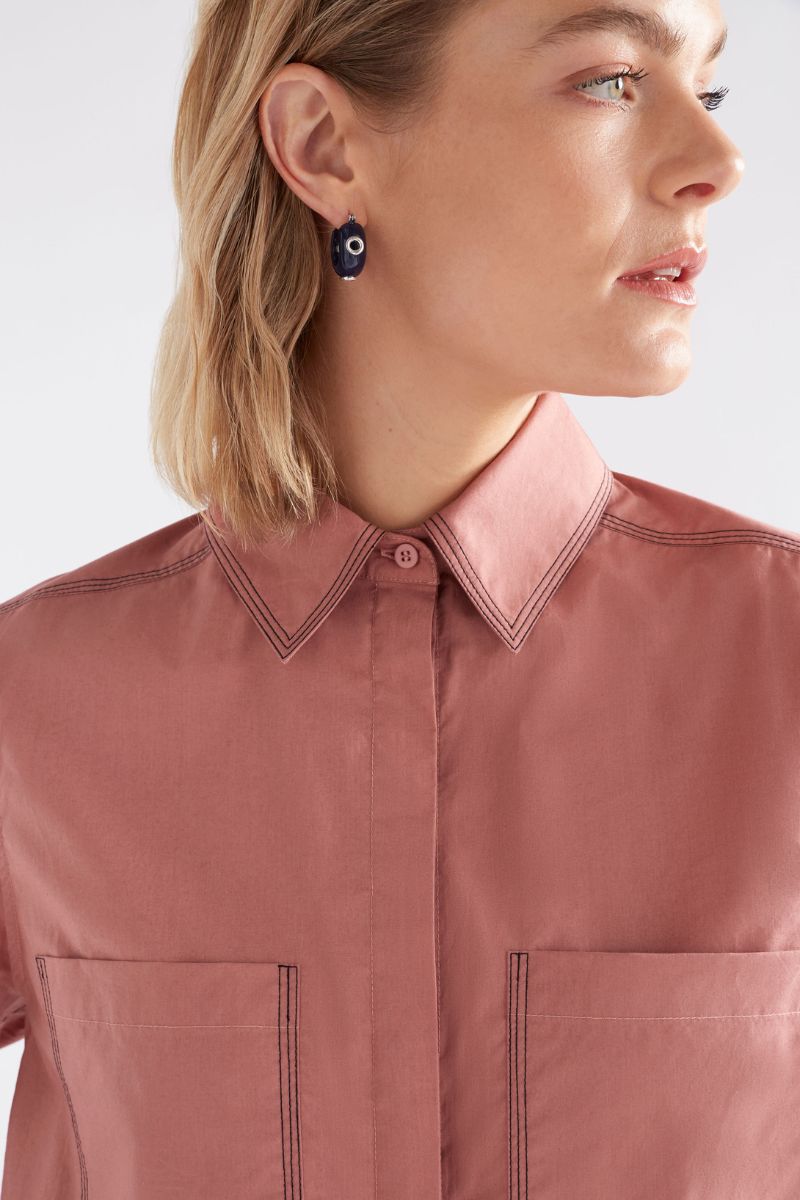 Close-up of a person wearing a pink shirt with a white background