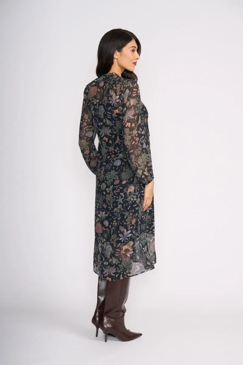 Woman wearing Tinder Twirl Dress in Narnia with a black background and multi pattern by FOIL FO8515 back view