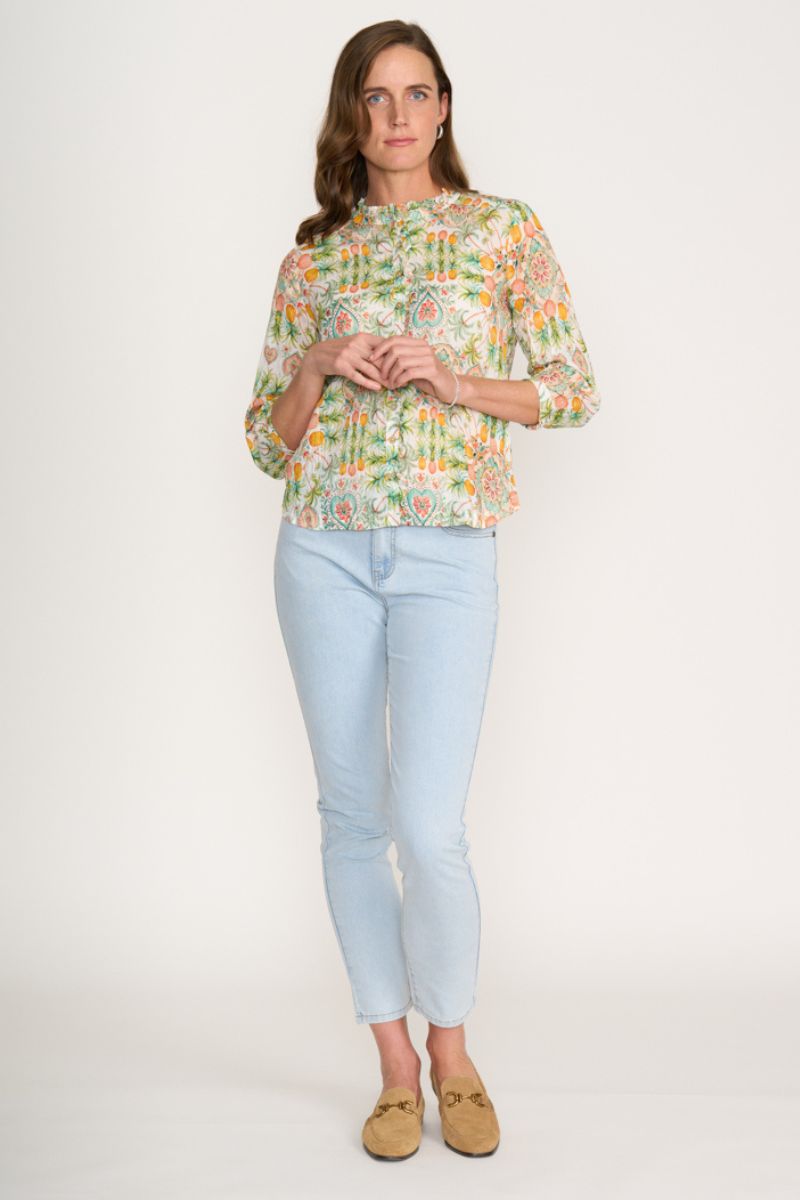 Woman wearing a floral blouse and light blue jeans on a white background