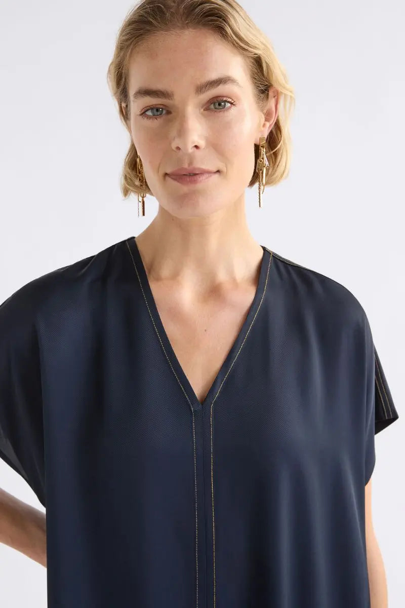 Woman wearing a navy blue dress close against a white background