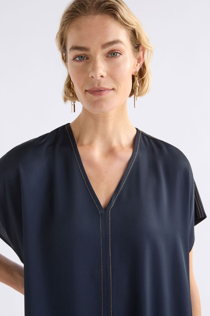 Woman wearing a navy blue dress close against a white background