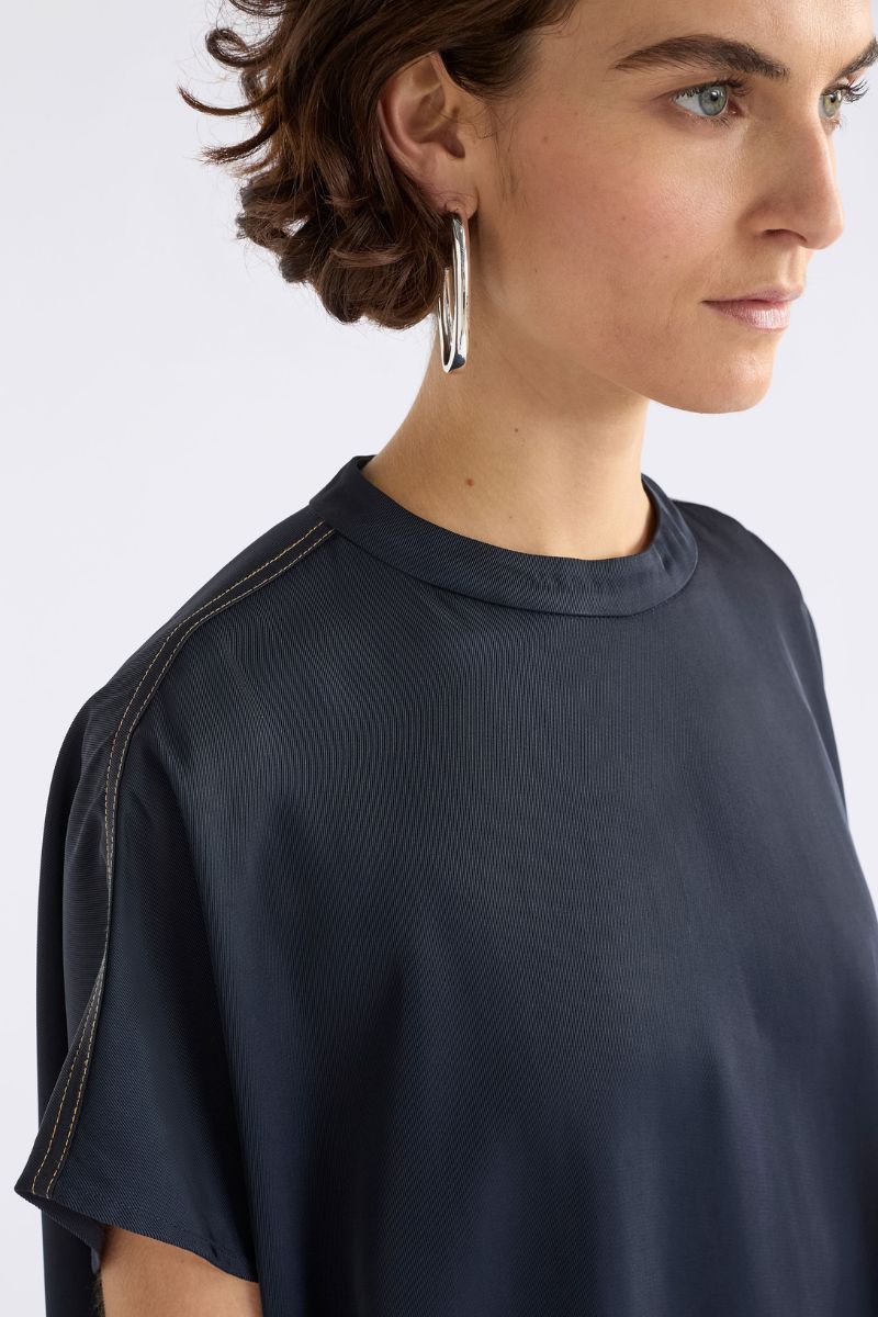 Person wearing a dark blue shirt with a plain background