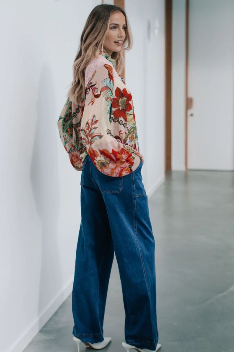 Side view of Woman wearing a floral blouse and blue jeans in an indoor setting