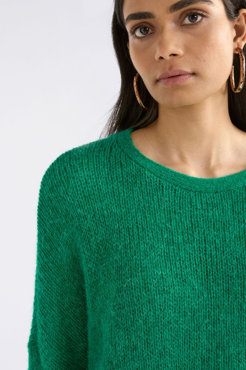 Woman wearing a green sweater against a white background