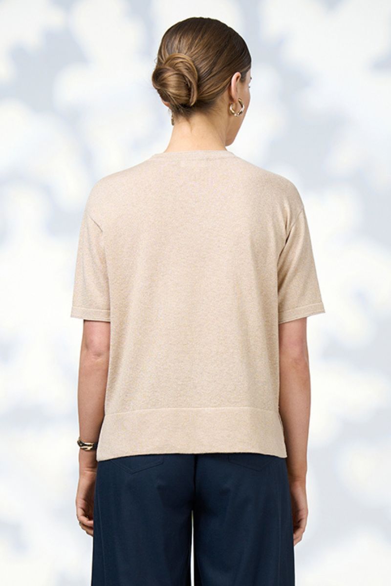 Back view of a champagne sparkly top and dark pants against a light blue sky background