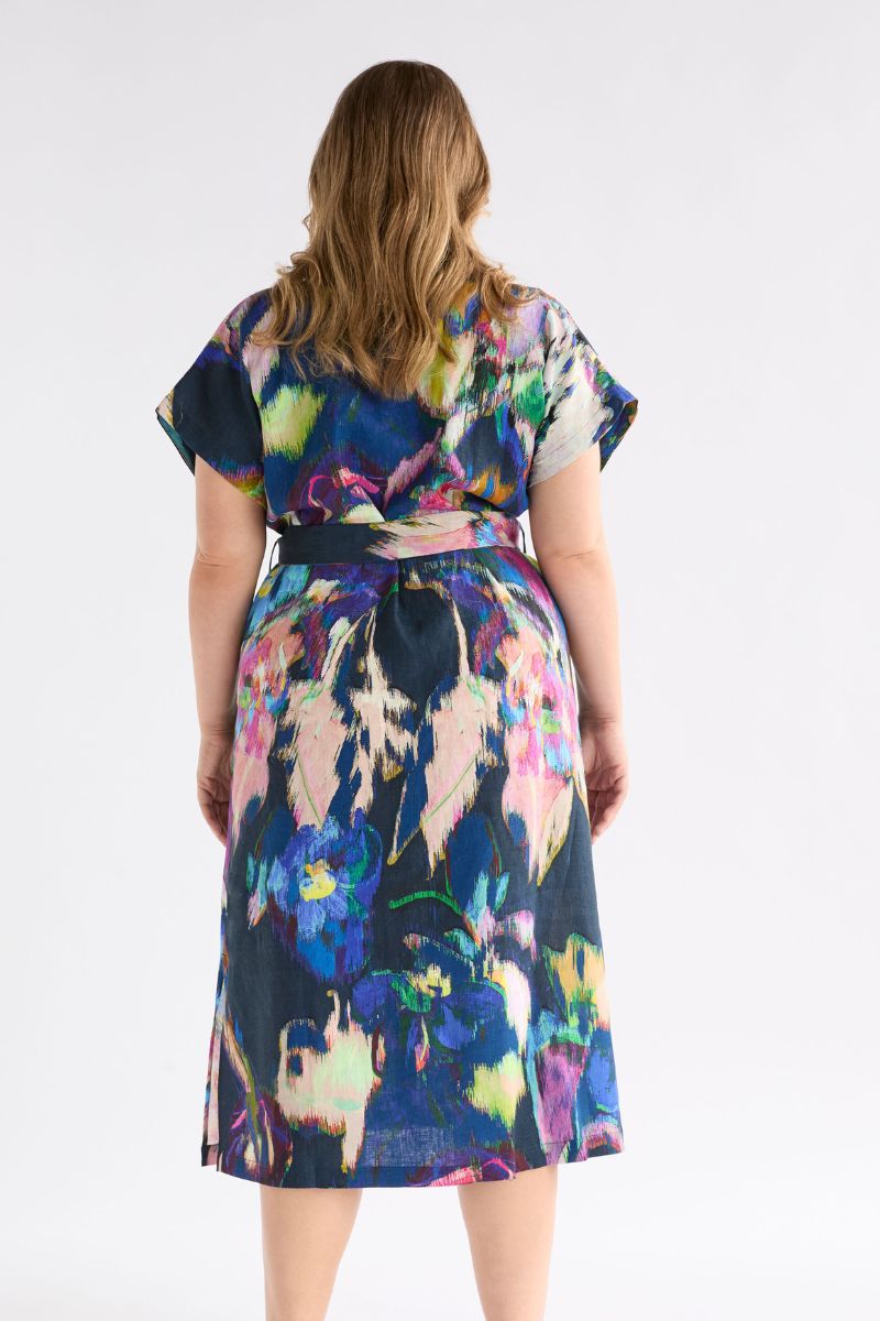 Back view woman wearing a colorful floral dress on a white background
