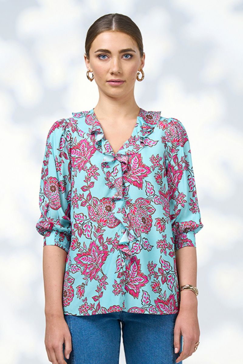 Woman wearing a blue floral blouse with a blurred white background