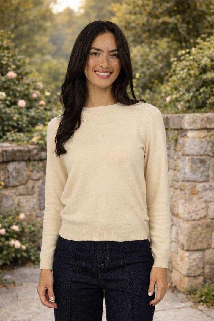 Woman wearing a mae sweater in butter colour by humidity lifestyle standing outdoors with greenery in the background
