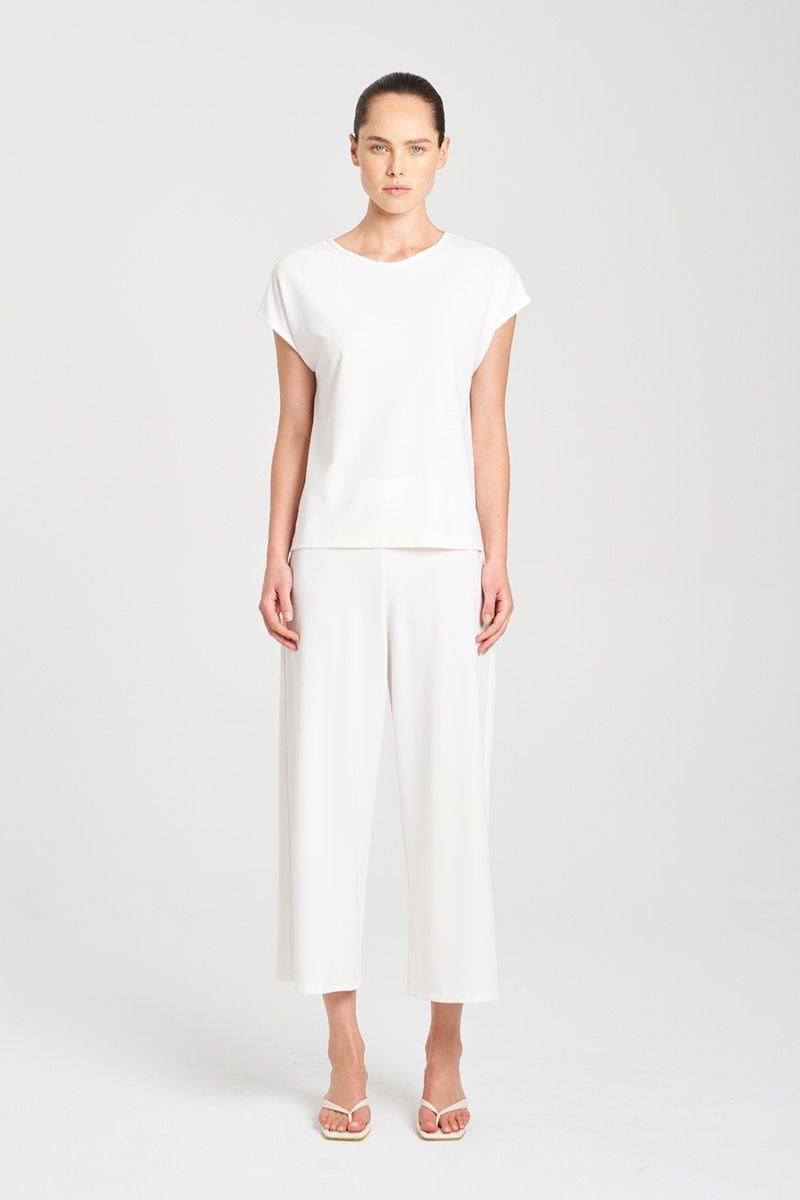 Woman wearing Cream outfit on white background the Mela Purdie capshell and Cropped plaza pant in F007 powderknit fabric 