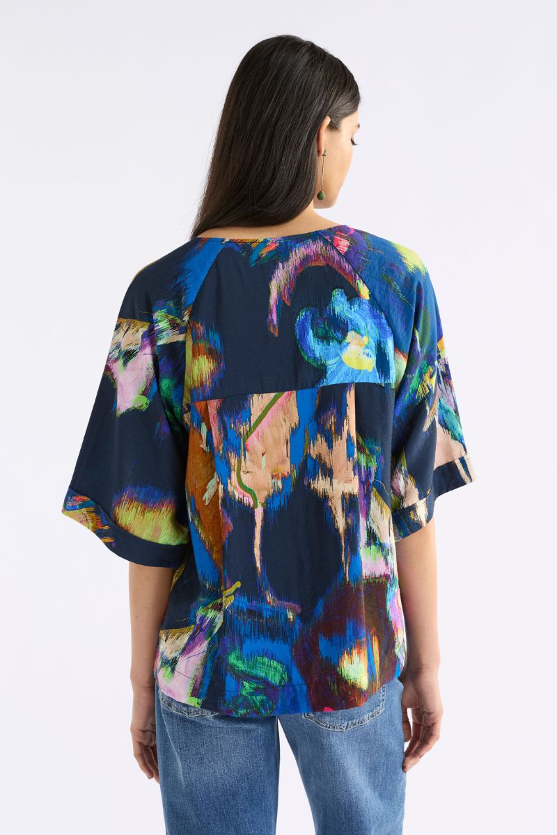 Back View Woman wearing a colorful abstract patterned top on a white background