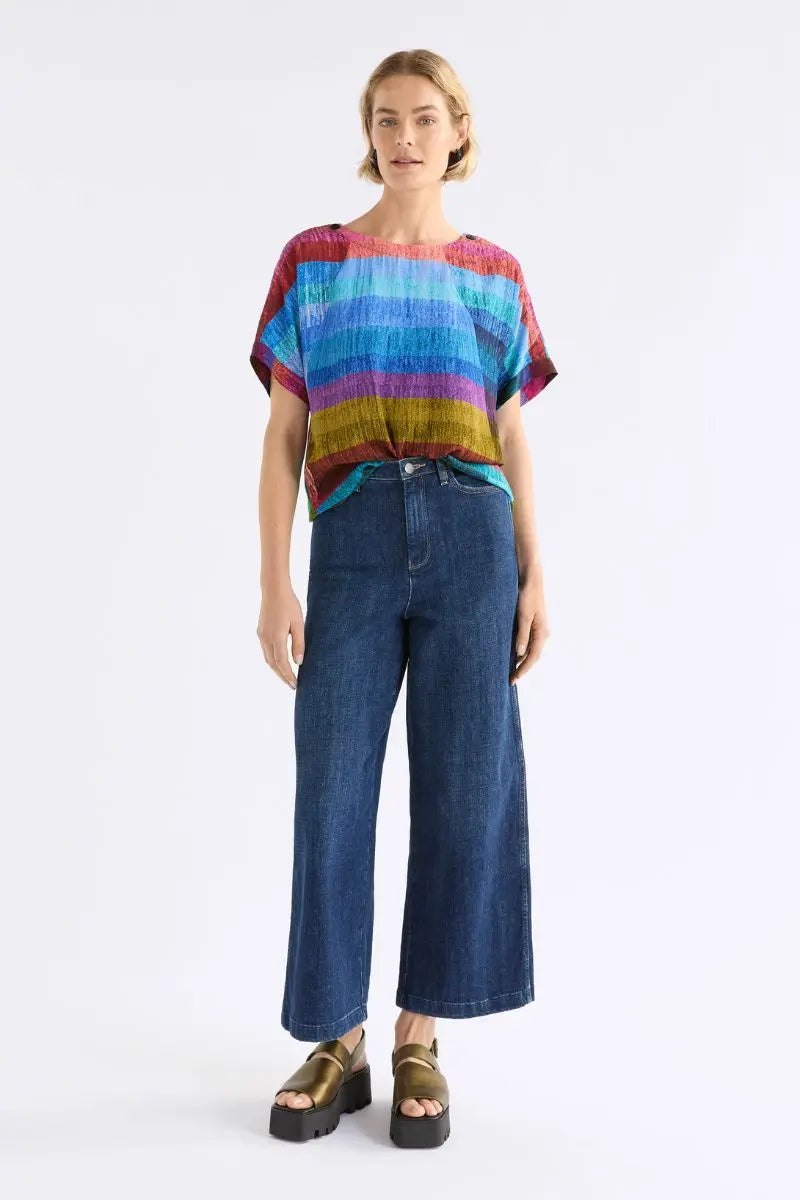 Person wearing a colorful striped shirt and blue jeans on a white background