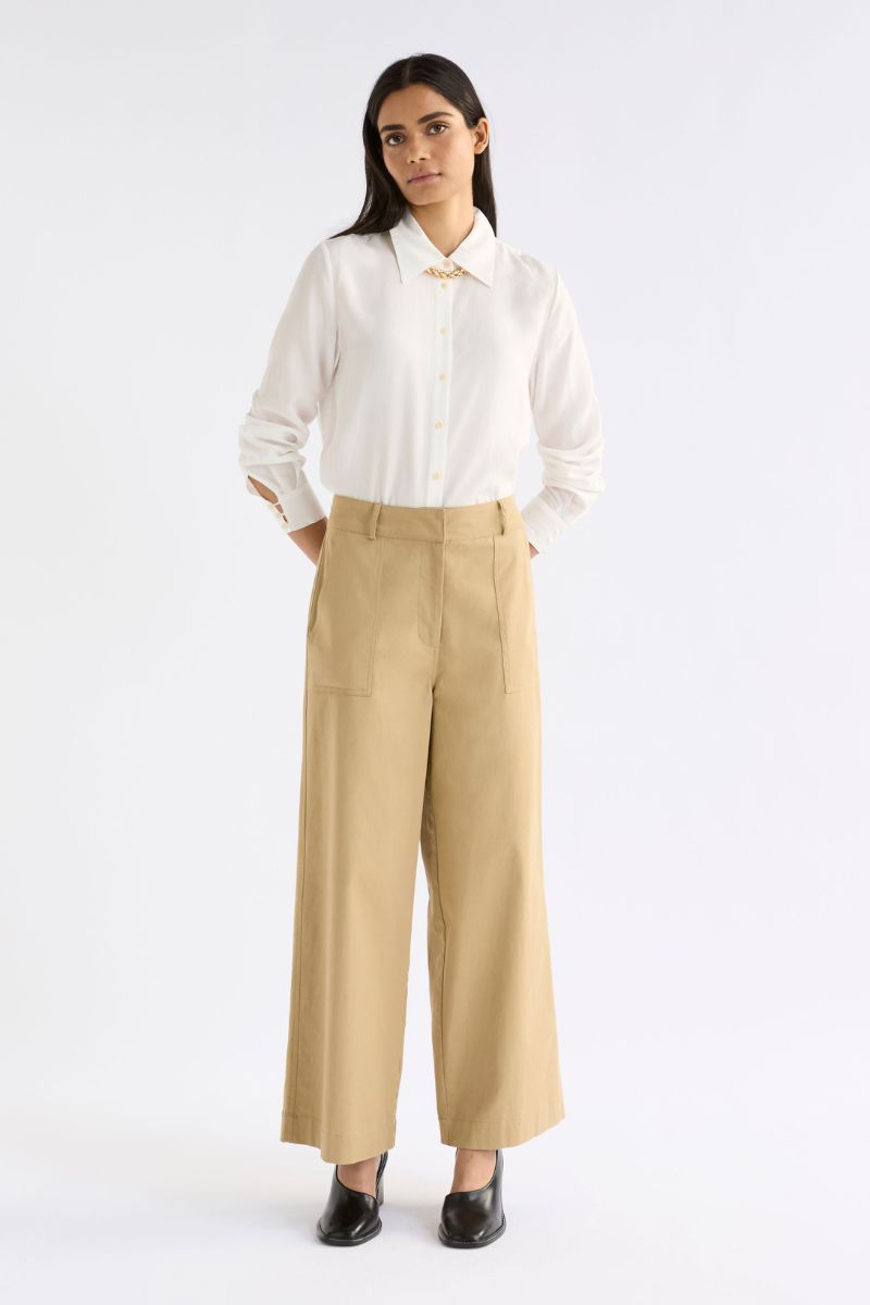 Woman wearing a white blouse and beige pants on a white background