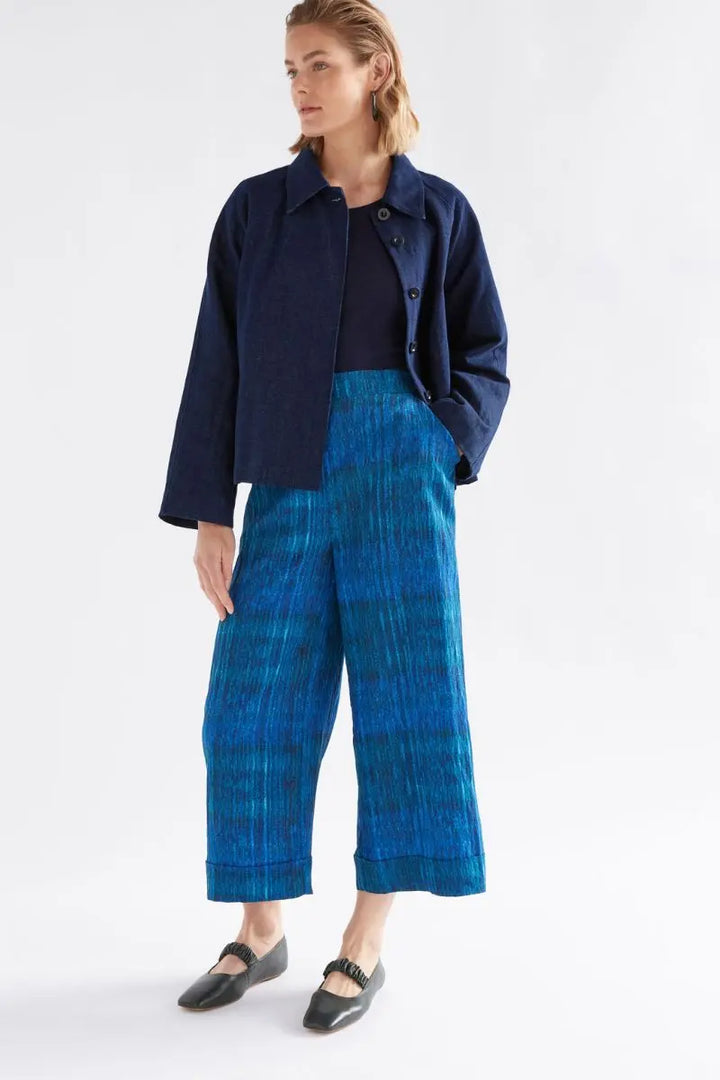 Woman wearing a navy jacket and blue plaid pants on a white background