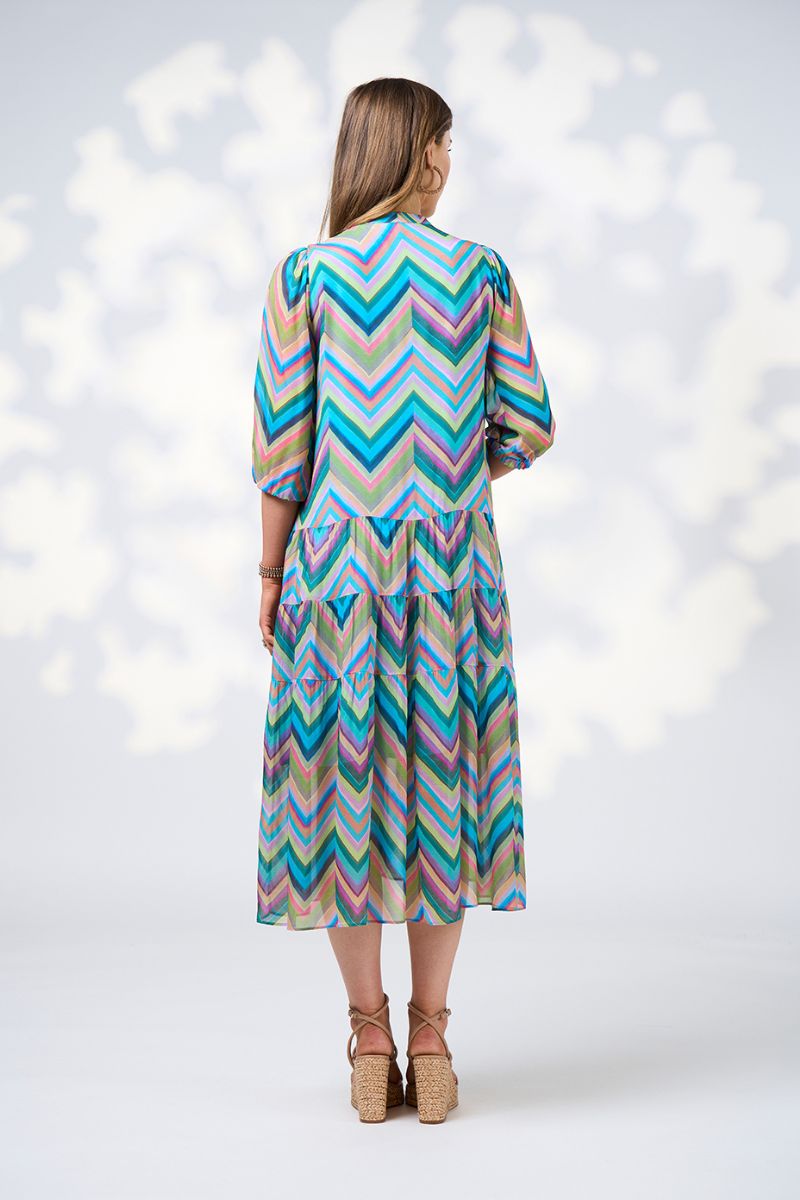back view Woman wearing a colorful zigzag patterned dress on a white background