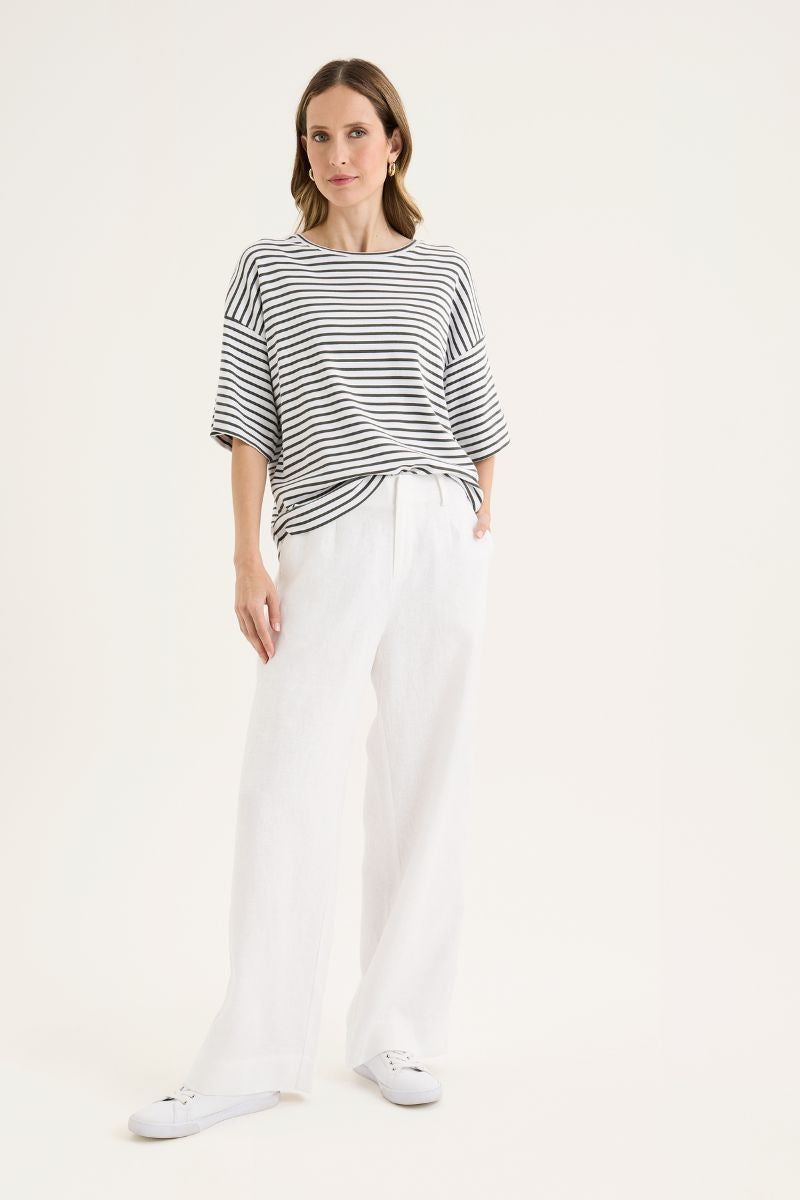 Woman wearing a striped shirt and white pants on a white background