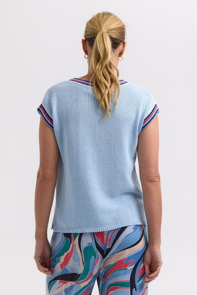 Woman wearing a light blue top with colorful pants on a white background