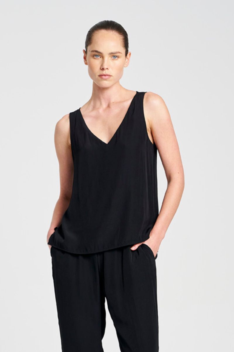 Woman wearing a black sleeveless top and pants on a light gray background