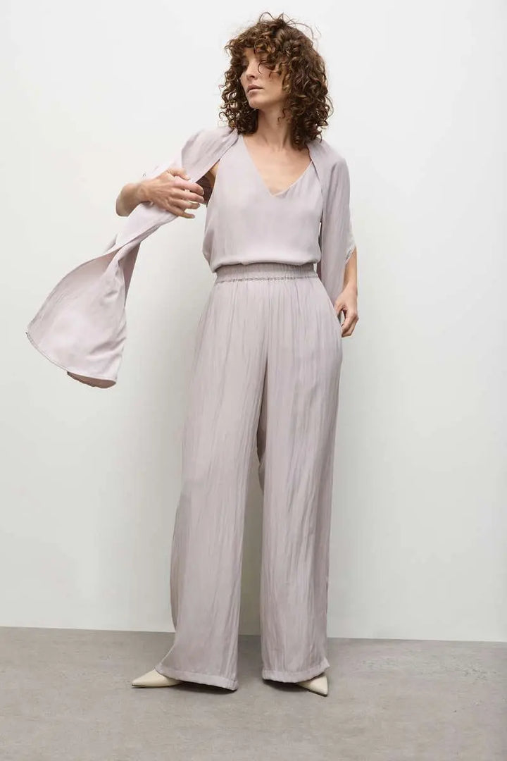A model wearing a sleeveless, v-neckline Audrey Tank top in a solid color, showcasing a relaxed fit with a high-low hem.