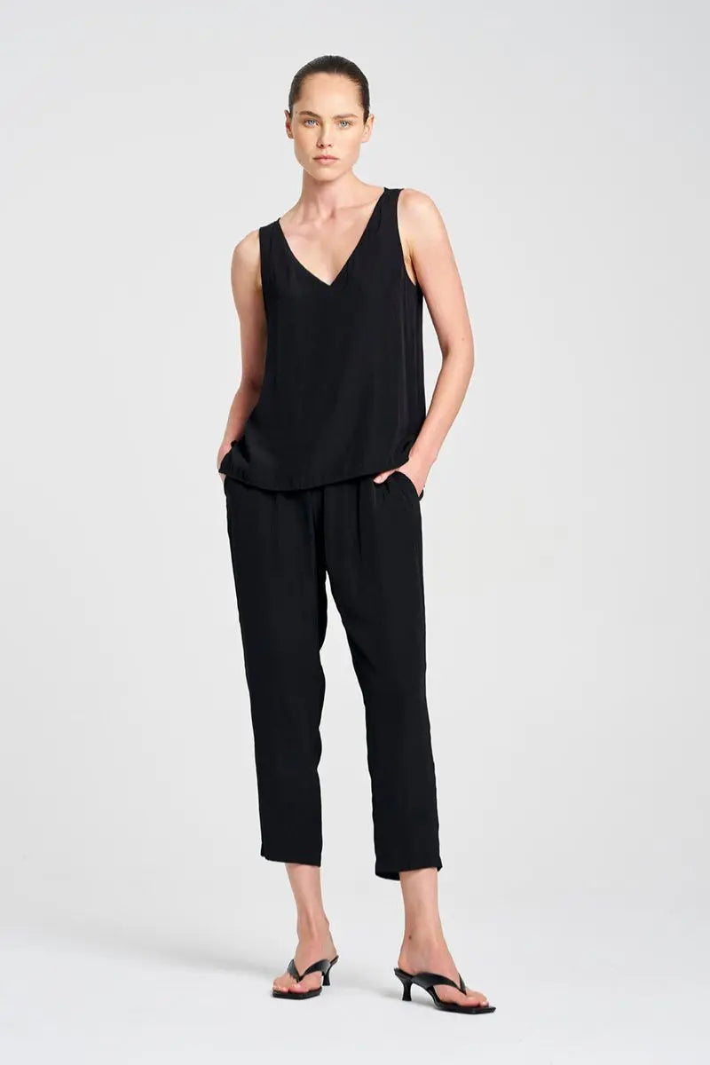 Woman wearing a black sleeveless top and pants on a white background