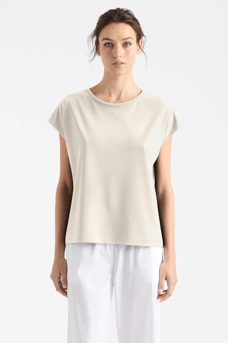 Woman wearing Mela Purdie Cap Shell F007 8365 in Oyster with white pants against a white background