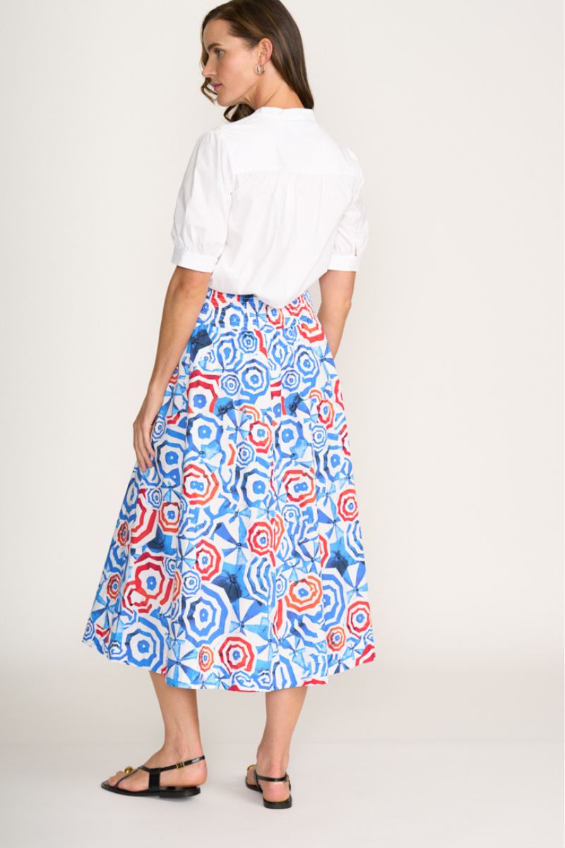 Woman wearing a white blouse and a colorful patterned skirt on a white background