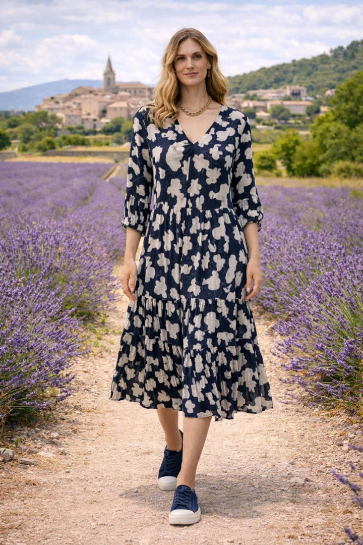 Woman in a dress addict organic cotton floral dress standing in a french lavender field with a village in the background