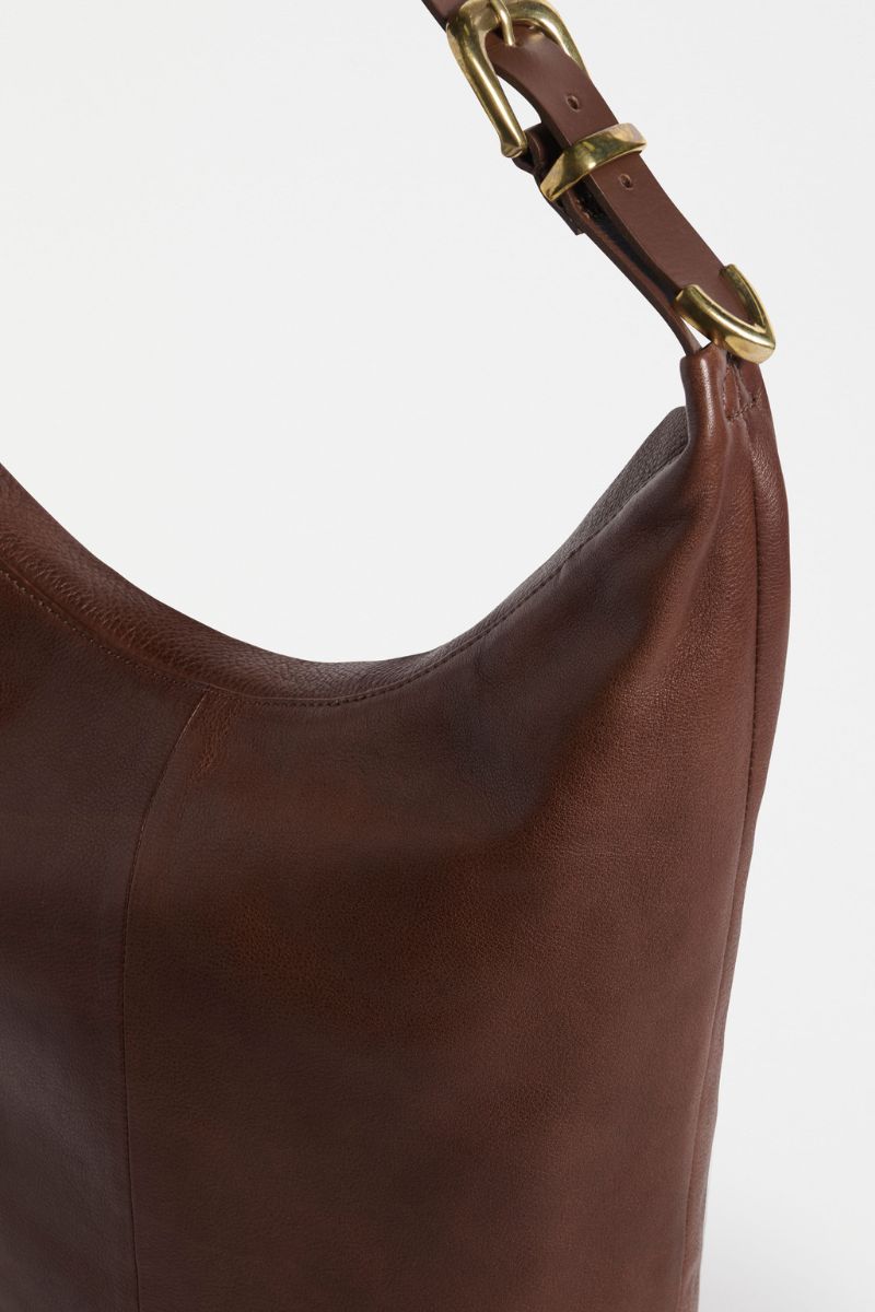 Brown leather handbag with a gold buckle on a white background